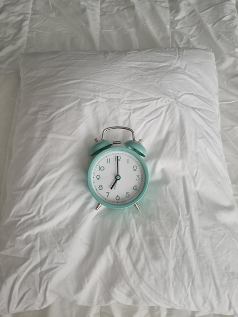 Alarm clock for seven o'clock on white bed closeup