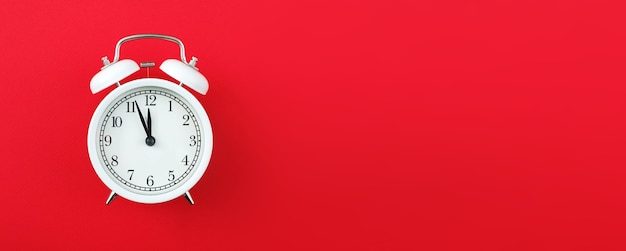 Alarm clock showing five minutes to twelve on a red background