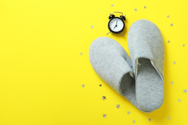 Alarm clock and slippers on yellow