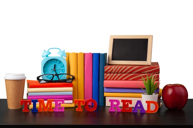 Alarm clock stack of books and cup on tabletop against white background