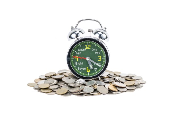 Alarm clock standing with coins isolated on white background