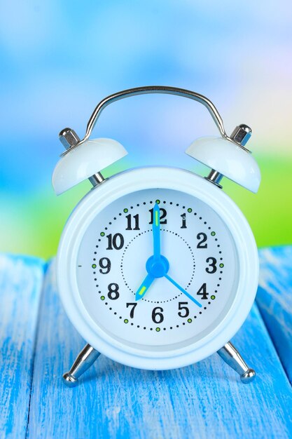 Alarm clock on table on blue background