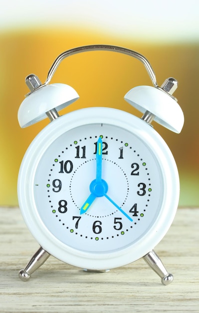 Alarm clock on table on bright background