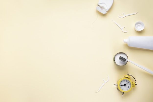 Alarm clock, toothbrush and tooth powder on yellow