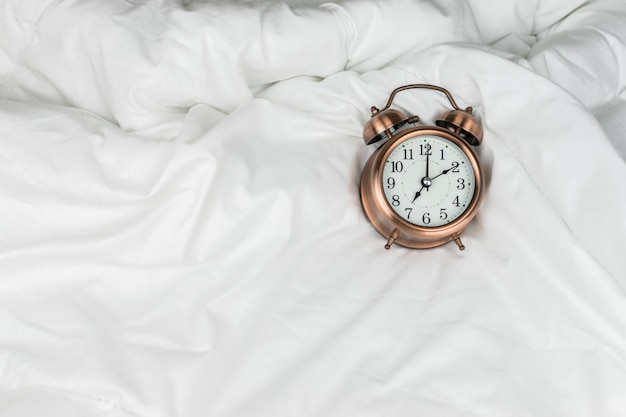 Alarm clock on the white bed