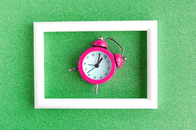Alarm clock and white photo frame on color background Minimal concept