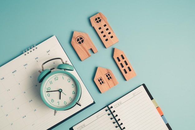 An alarm clock with calendar notebook and wooden house model