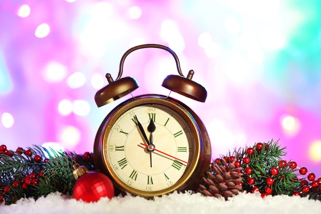 Alarm clock with Christmas decorations on bright background