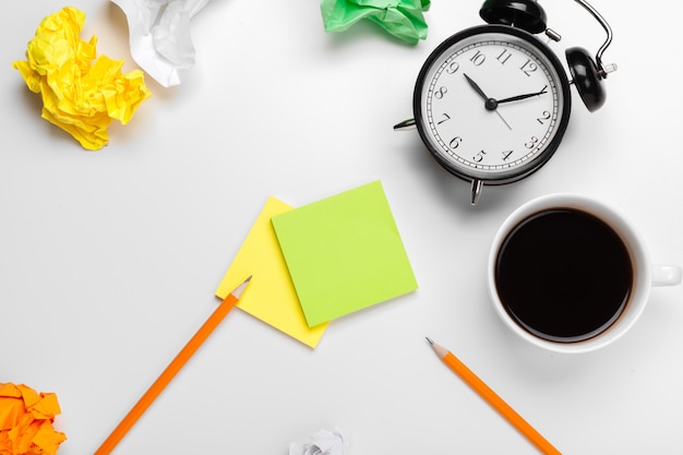 Alarm clock with crumpled paper balls and coffee cup