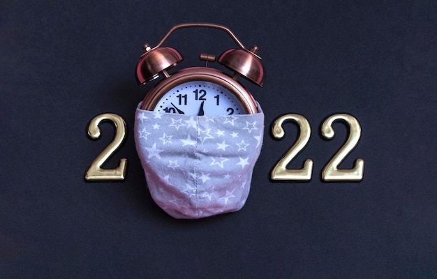 Alarm clock with gold numbers on a black background. Minimal concept of the new year 2022