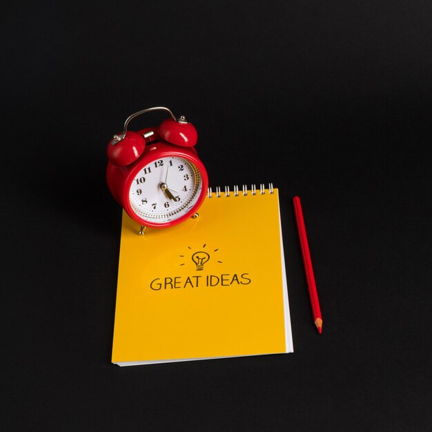 Alarm clock with notepad and colored pencils on black background Back to school great ideas