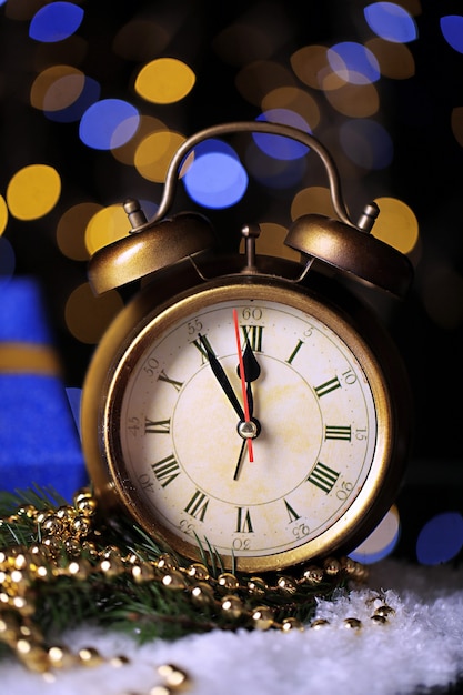 Alarm clock with snow and Christmas decorations on table on bright surface