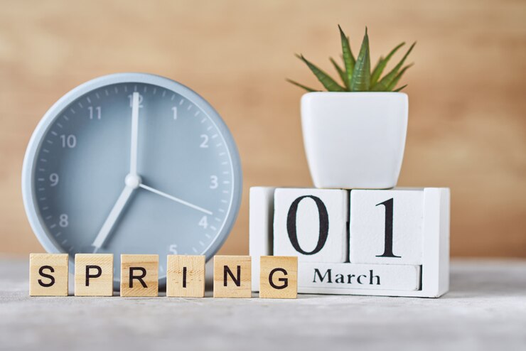 फोटो alarm clock with wooden block calendar date 1st march and plant on table