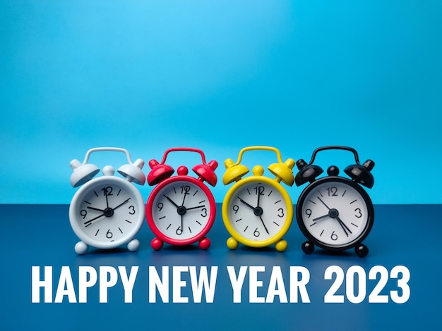 Alarm clock with the word HAPPY NEW YEAR 2023 on blue background