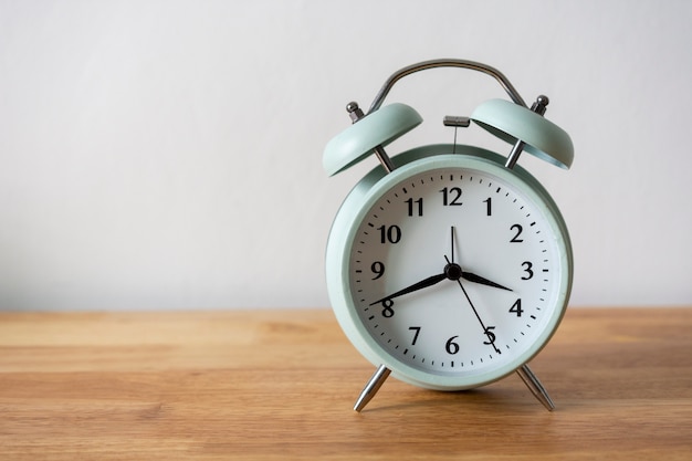 Alarm clock on wood table and white background.