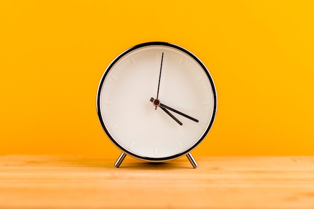 Alarm clock on yellow background time concept