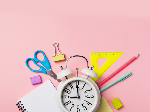 Alarm with colorful supplies on pink