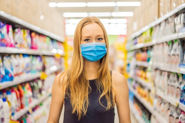 Alarmed female wears medical mask against coronavirus while grocery shopping in supermarket or store health safety and pandemic concept young woman wearing protective mask and stockpiling food