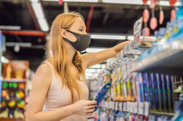 Alarmed female wears medical mask against coronavirus while purchase of household chemicals in