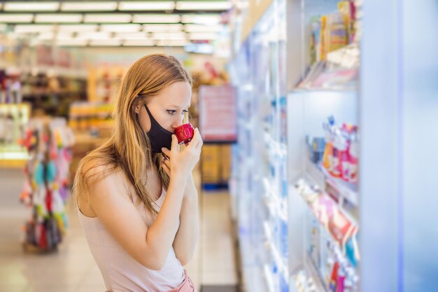 Alarmed female wears medical mask against coronavirus while purchase of household chemicals in