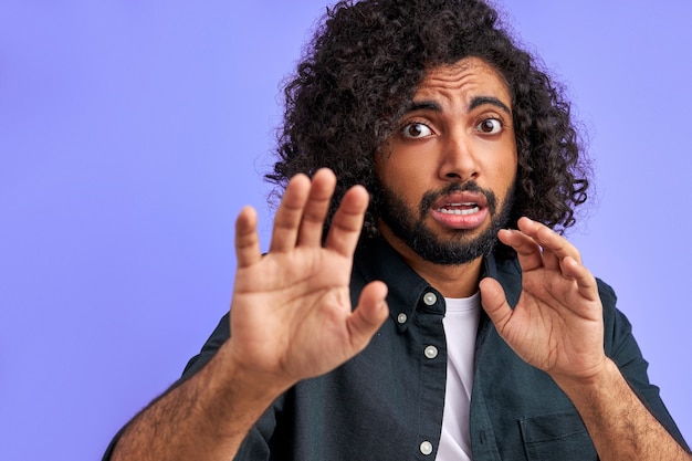 Alarming scared panicking man is gesturing stop, afraid of something