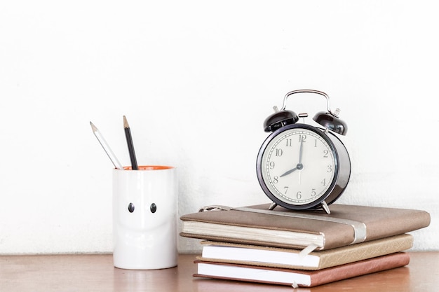 Alarmklok op boeken over tafel tegen een witte achtergrond