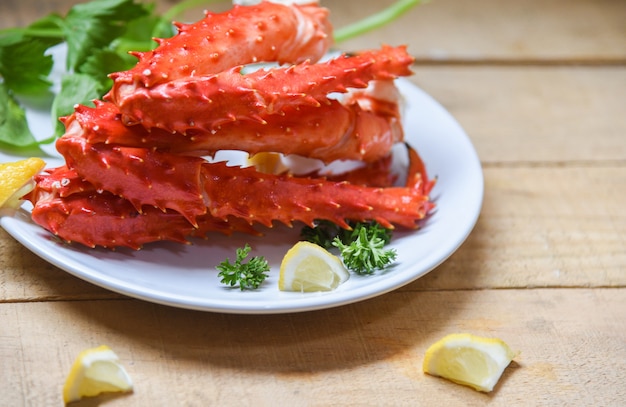 Alaskan King Crab Legs cooked seafood with lemon spices on white plate in the wooden table -