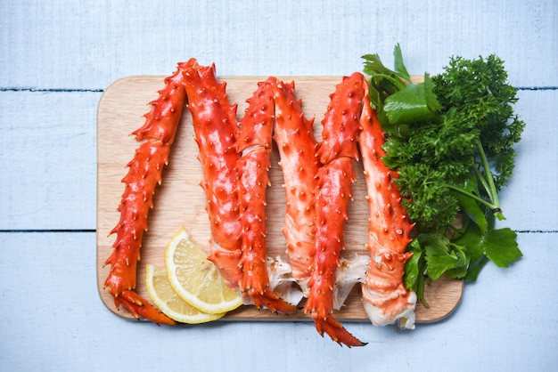 Alaskan King Crab Legs Cooked on wooden cutting board with lemon parsley 