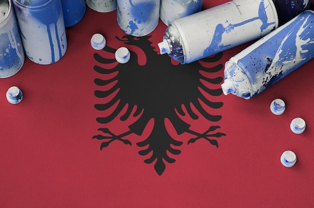 Albania flag and few used aerosol spray cans for graffiti\
painting street art culture concept