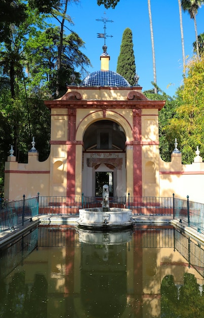 Alcazar Gardens boasts the small Pavilion of the Lion with preserved inner frescoes facing the small pond with the lion fountain in Seville Spain