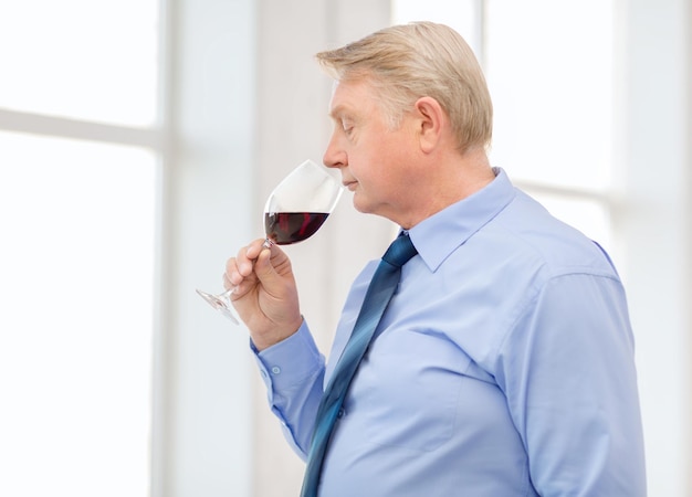 alcohol and beverage concept - older man smelling red wine