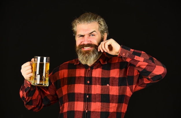 Foto bevanda alcolica hipster al bancone del bar divertirsi hipster moderno che si ubriaca la sete ha bisogno di una grande birra fredda l'uomo barbuto brutale beve birra birreria barista al bar l'uomo tiene un boccale di birra