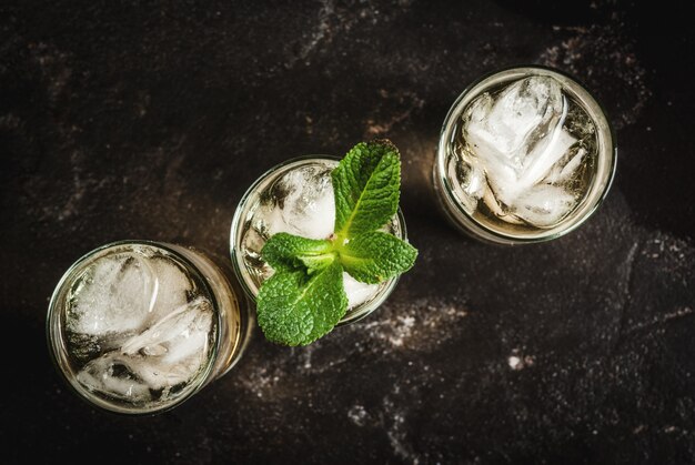 Alcohol cocktail made from golden tequila with ice cubes and mint On a black concrete table