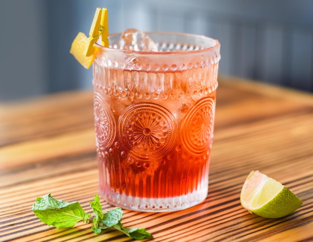 Alcohol cocktail on wooden table against dark wall with copy space