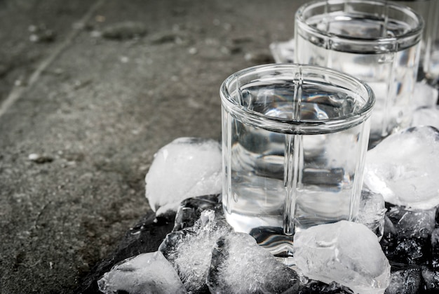 alcohol and cocktails. three glasses of vodka on a slate tray, with ice. on a black stone table, 