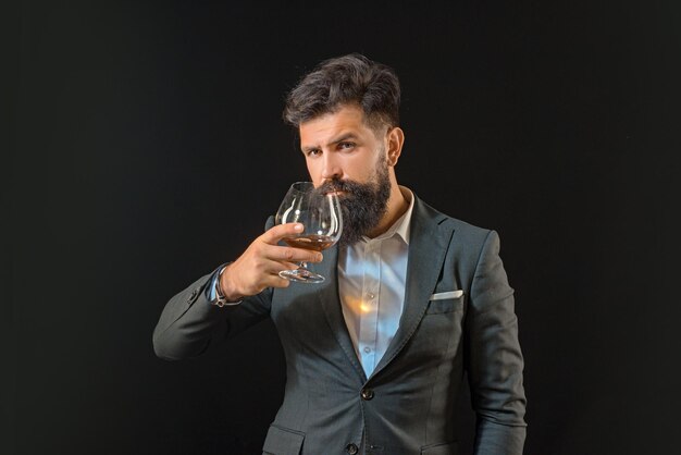 Alcohol concept luxury beverage concept man bartender with beard holds glass brandy fashion style co