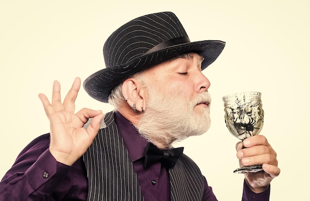 Alcohol drink and bar Bearded old guy hold wineglass with spider inside Extreme lifestyle Bartender enjoy weird cocktail Delicious cocktail for brave man Exotic food Cocktail with real spiders