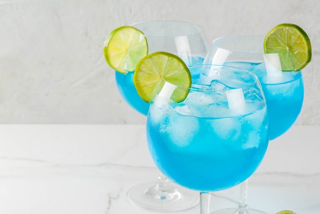 Alcohol drink. Glasses with a blue alcoholic cocktail with ice and lime garnish. Blue Curacao. Liquor. 