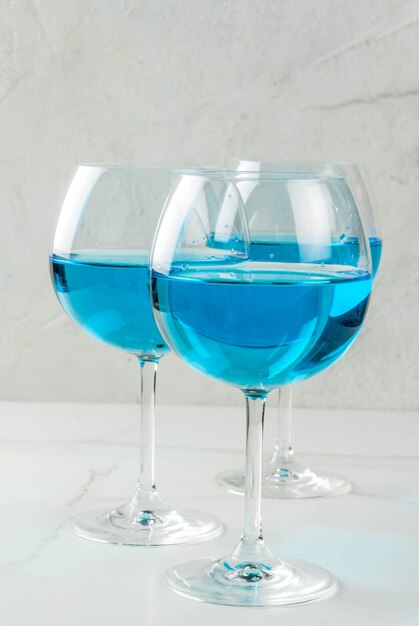 Alcohol drinken. Glazen met trendy blauwe wijn, op witte marmeren tafel.