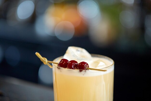 alcohol drinks and luxury concept - close up of cocktail glass with cherries at bar