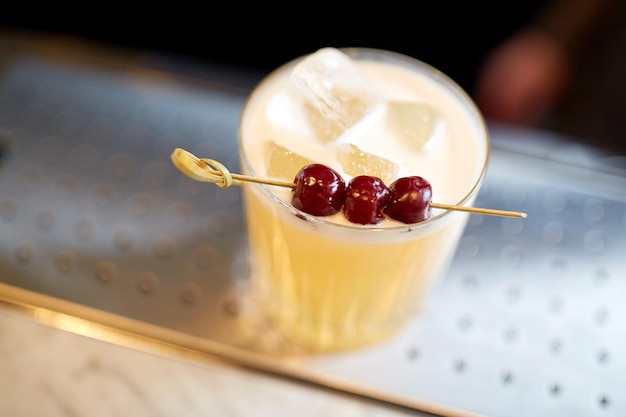 alcohol drinks and luxury concept - glass of cocktail with cherries at bar