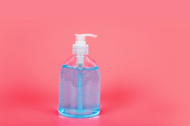 Спиртовой гель Sanitizer для рук гель-очистители для борьбы с бактериями и вирусами на розовом фоне, Люди, использующие спирт-гель для мытья рук для предотвращения коронавируса (COVID-19)