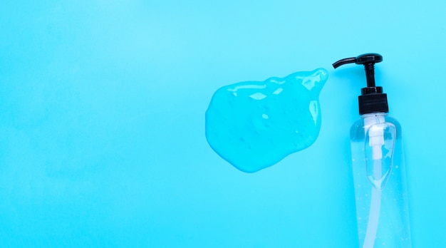 Alcohol hand sanitizer gel in pump bottles on blue background. Copy space