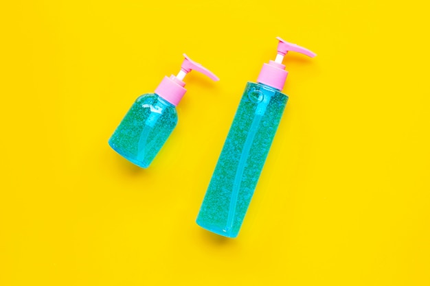 Alcohol hand sanitizer gel in pump bottles on yellow background.