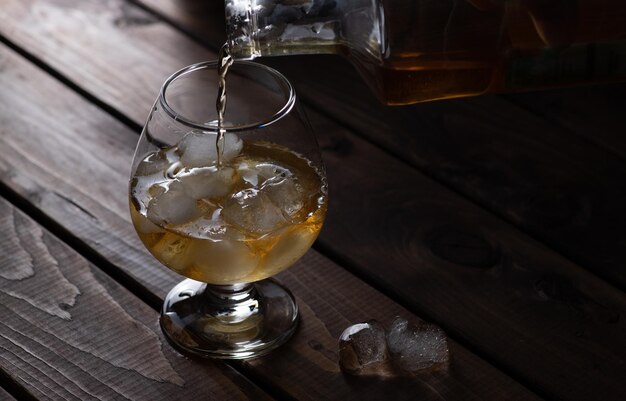 Alcohol is poured on ice in a macro glass