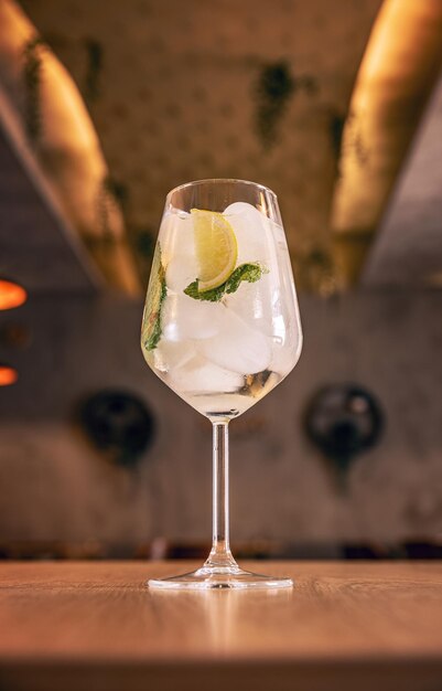 Alcohol refreshing cocktail with lemon and cucumber on bar table