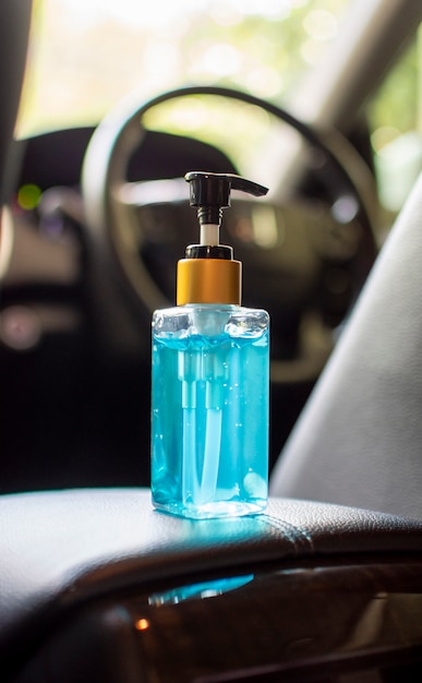 Alcohol sanitizer bottle place on leather armrest in a luxury car,