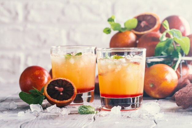 Alcohol tequila sunrise cocktail with red orange, ice and mint