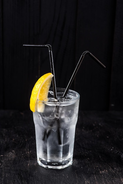 Alcohol transparante cocktail met ijs en citroen op zwarte achtergrond