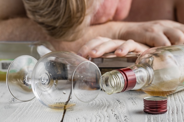 Alcohol verslaafd man aan de tafel. Triest depressieve mannelijke volwassene problemen met alcohol.